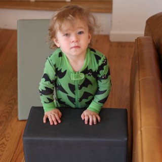 Curious Toddler in Green Dinosaur Pajamas at Home