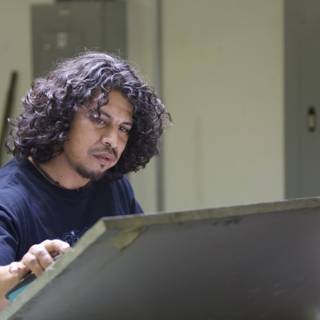 Curly Haired Man Working on a Metal Desk