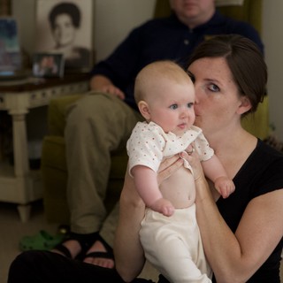 Mother Kisses Infant in Warm Family Living Room
