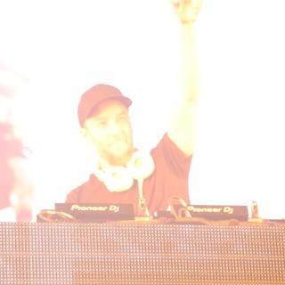 DJ Raises Hand Amid Blazing Stage Lights at Festival