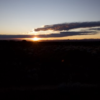 Dramatic Sunset Over Desert Landscape with Silhouetted Scrubland
