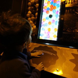 Child Playing Interactive Ball Counting Game at Science Museum