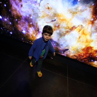 Child Exploring Cosmic Nebula Display at Space Center