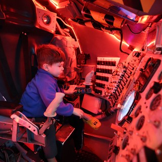 Young Visitor Explores Submarine Control Room Exhibit