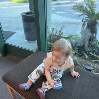Toddler Playing with Toy Phone in Modern Cafe