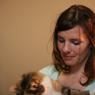 Tender Moment: Woman Cradling Calico Kitten Indoors