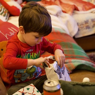 Young Child Opening Christmas Presents in Cozy Living Room