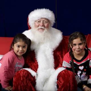 Santa Claus Visits Two Girls on Red Sofa