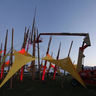 Crane lifting a large structure with flags at Coachella