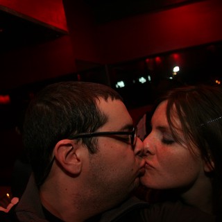 A Couple Sharing a Kiss at a Dimly Lit Bar