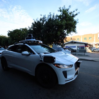 Autonomous Waymo Vehicle on Urban Street at Dusk
