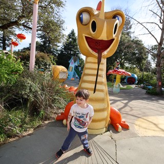 Young Boy Walking Past Giant Dragon Slide at Theme Park