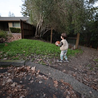 Young Child with Football on Suburban Street at Dusk