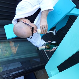 Man Enjoying Champagne on Turquoise Outdoor Furniture