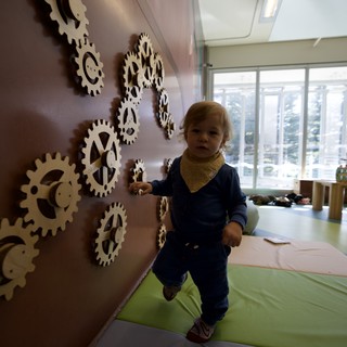 Toddler Playing on Interactive Gear Wall Installation