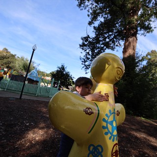 Child Hugging Large Yellow LEGO Figure at Theme Park