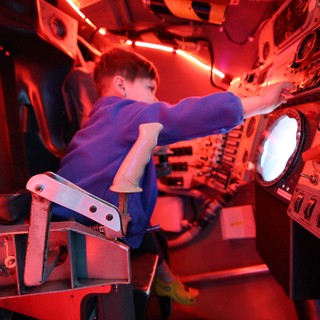 Young Astronaut Training in Red-Lit Space Capsule Simulator