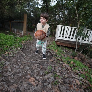 Young Boy Playing Basketball in Backyard Garden