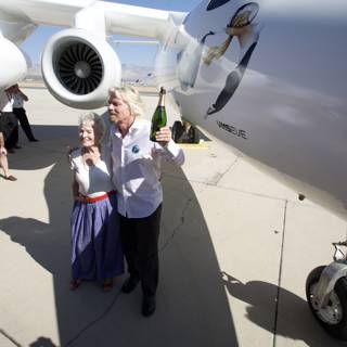 Richard Branson and a Woman Pose with Aircraft on Airfield