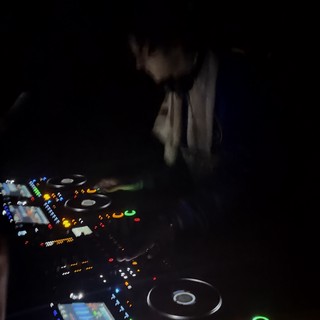 DJ Performing in Dark Nightclub with Illuminated Equipment