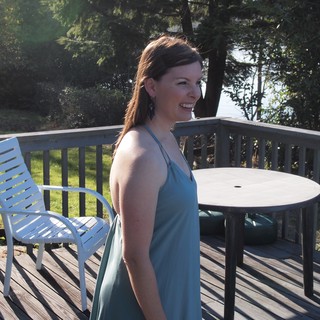 Woman in Teal Dress Smiling on Sunny Deck