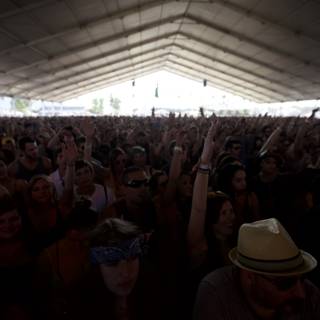 Hands Up for the Music Caption: A crowd of ten people with fedoras and cowboy hats raise their hands in excitement at Coachella 2012.