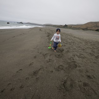 Young Explorer Walking Along a Gray Sandy Beach
