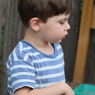Young Boy in Striped Shirt Looking Down Thoughtfully
