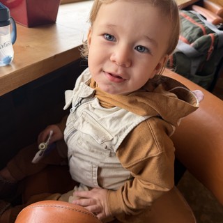 Cheerful Toddler in Beige Overalls at Home