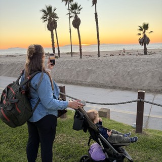 Mother Capturing Sunset Beach Moment with Child