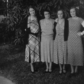 Four women in beautiful dresses posing for a photo