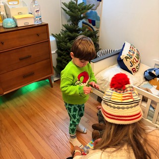 Young Child Examining Art or Toy by Christmas Tree