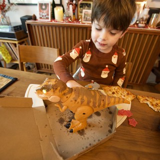 Child Delighting in Dinosaur-Shaped Christmas Pizza