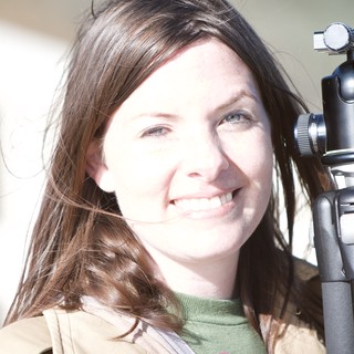 Smiling Photographer Holding Tripod in Bright Sunlight
