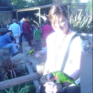 Woman bonding with her feathered friends Caption: A woman holds a parrot and a parakeet while enjoying a sunny day in the garden.