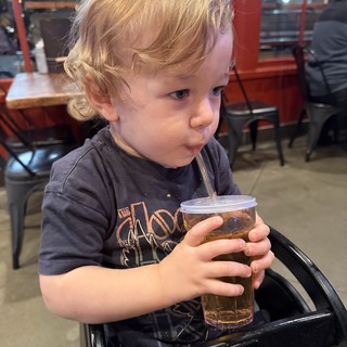 Toddler Enjoying a Drink at Local Restaurant