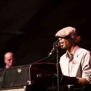 Hat-clad Man Rocks His Keyboard on Stage