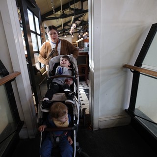 Parent Navigating Narrow Restaurant Stairwell with Double Stroller