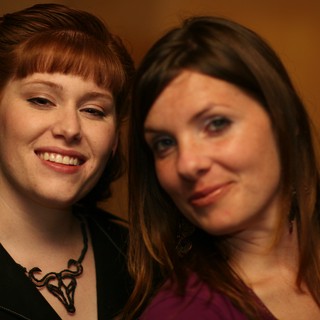 Two Women Smiling Together at Indoor Event