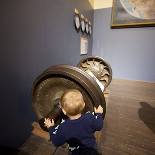 Young Child Exploring Antique Train Wheel at Museum