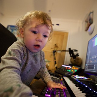 Young Child Exploring Music Production Equipment at Night