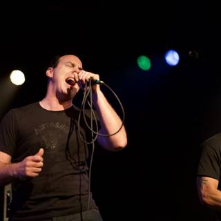Two Men on Stage Singing with Microphones