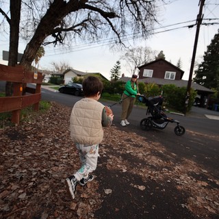 Child Running Towards Parent with Stroller on Suburban Street