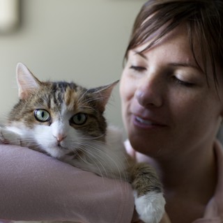 Woman Tenderly Holds Tabby Cat Indoors