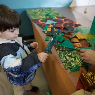 Young Child Explores Dinosaur Toy at Interactive Play Table