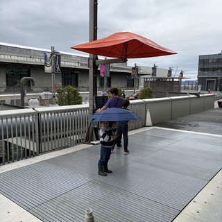 Child with Blue Umbrella on Modern Waterfront Plaza