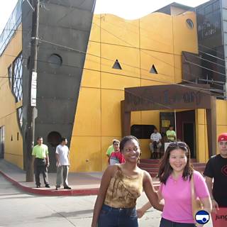 Three People Pose in Front of Yellow Ensenada Building