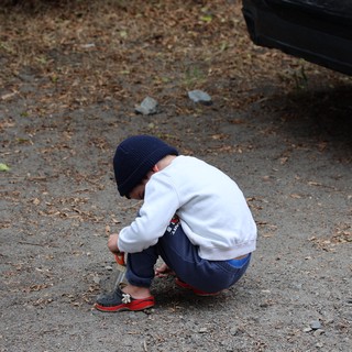 Young Boy Explores the Ground at Campsite