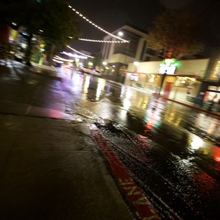Rain-Slicked City Street at Night with String Lights