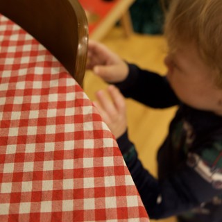 Young Child Reaching for Red Checkered Chair Cushion